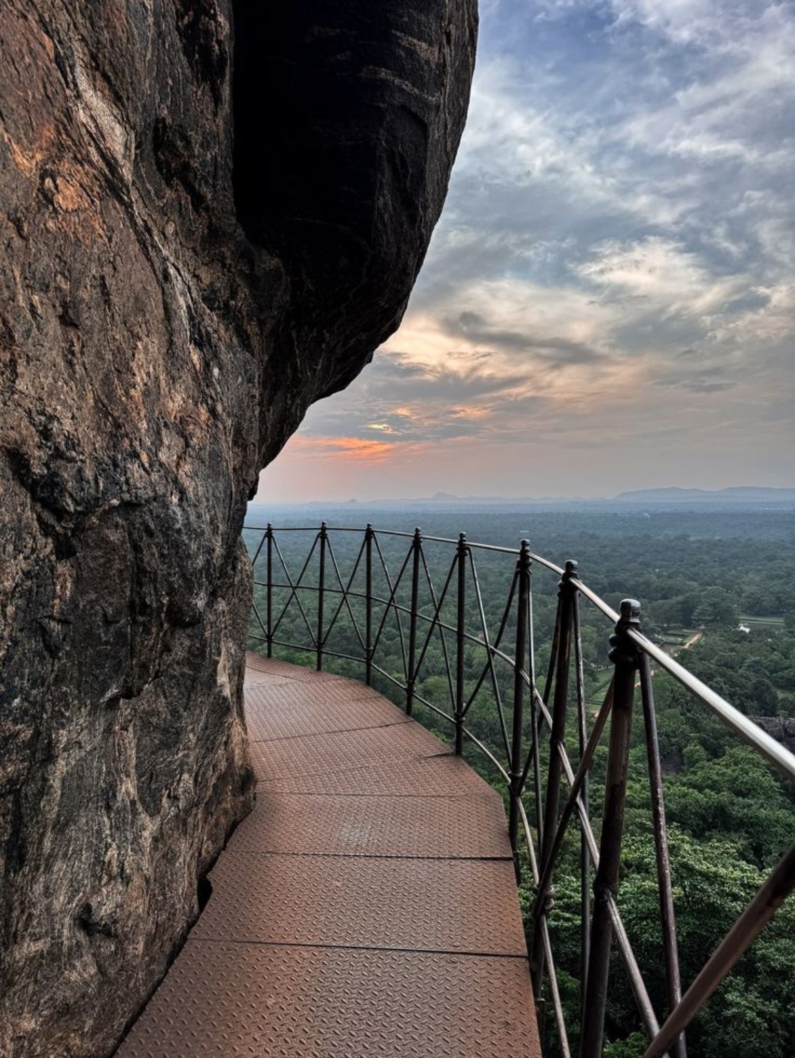 Walkway carved along the Sigiriya rock face overlooking the plains